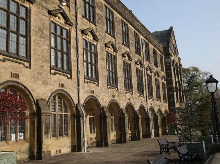 University building with natural stone work , arches, benches outside and old windows.