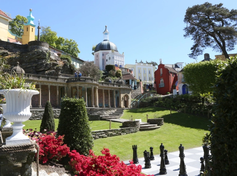 Manicured green lawn white buildings in background with giant chess board and plants on lawn.