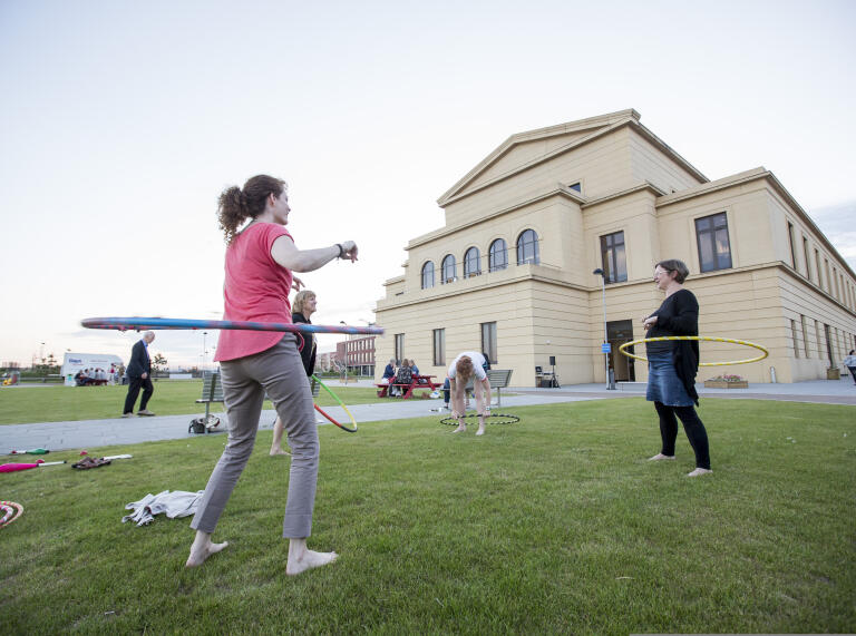 Delegates hula-hooping on the grounds of a university venue.