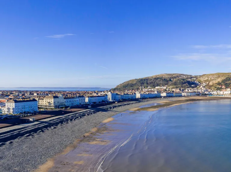 The shoreline of a beach resort lined with hotels with cliff tops beyond.