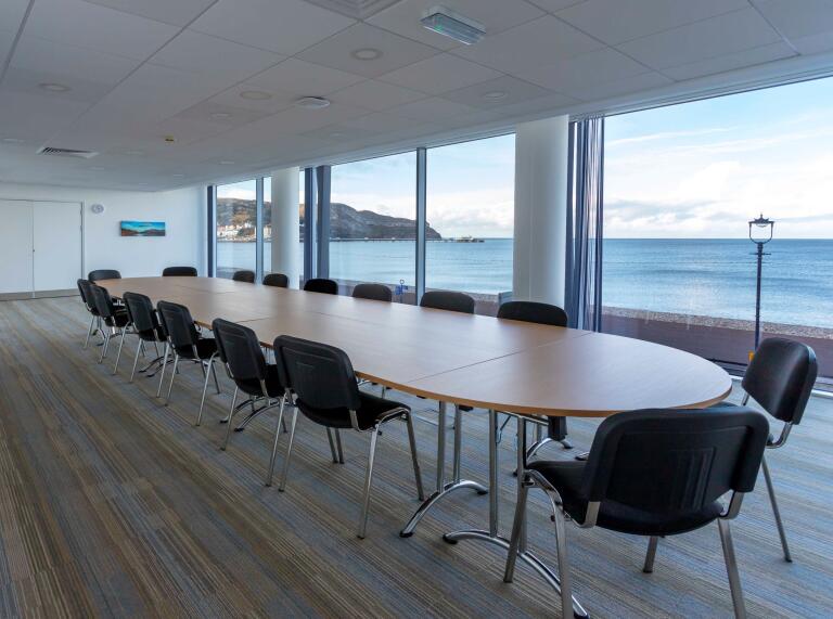 Boardroom with floor to ceiling windows looking out to sea.