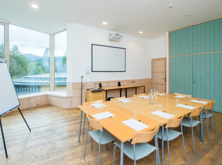 Table and chairs set for a meeting with whiteboard and flipchart.