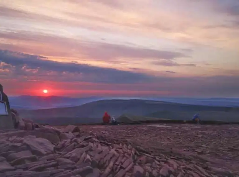 Pen y Fan sign at mountain top with sunset in the background