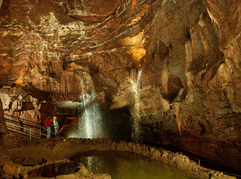 Two people in the underground caves with waterfalls