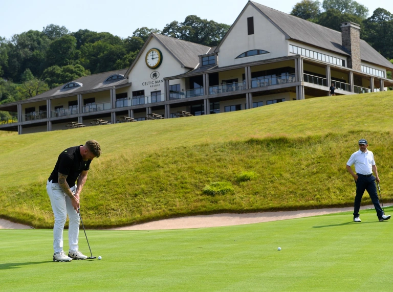 Golfers on the green with the clubhouse in the background.