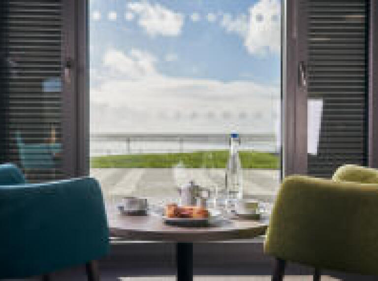 set tabel and chairs in the accommodation looking out at the sea and sands at Pendine Sands
