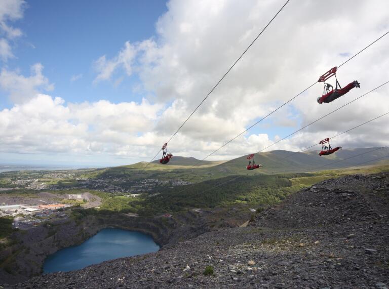 People zipping down a former quarry and the blue reservoir below