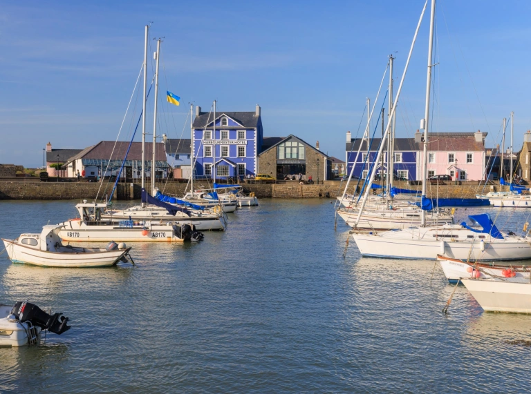 boats on blue water in harbour with hotel painted blue in background