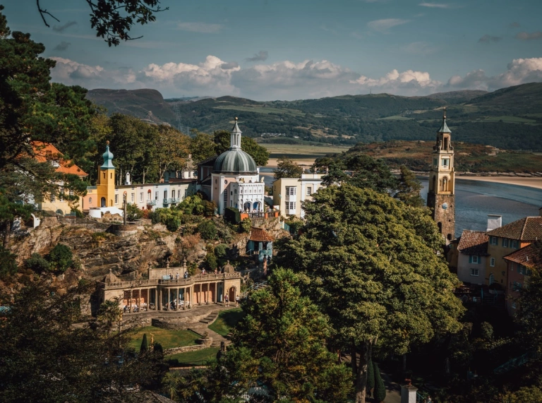 view over Portmeirion village with coloured buildings tress and the mountains and estuary in the background