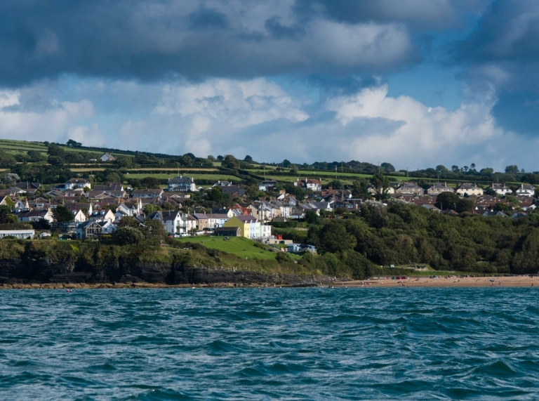 View of Cardigan bay from the sea with green mountains and sandy beach in front of blue sea