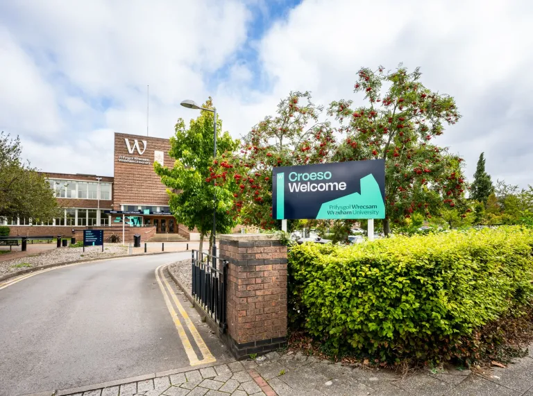 exterior of Wrexham University entrance with croeso welcome sign on hedge