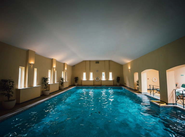 Indoor swimming pool with lounge chairs along the side