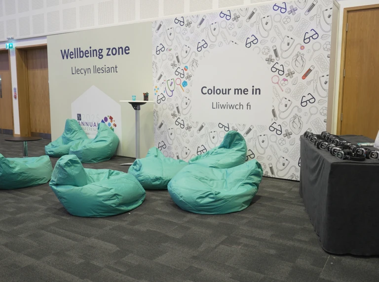 A wellbeing zone with several teal beanbags, a colouring wall display, and a table with headphones arranged on it.