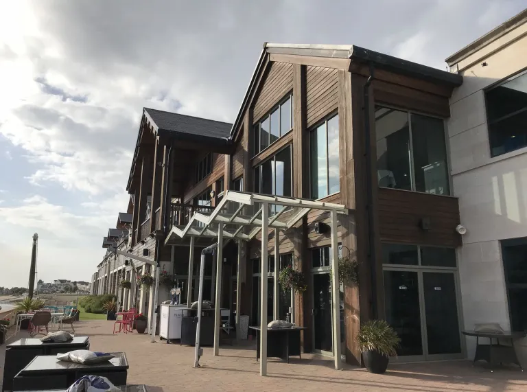 exterior of the Quay Hotel with reception area just behind the doors and benches outside overlooking the Estuary
