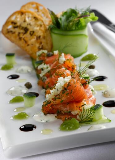 A plate of cured Halen Môn spiced salmon with cucunber and garnish.