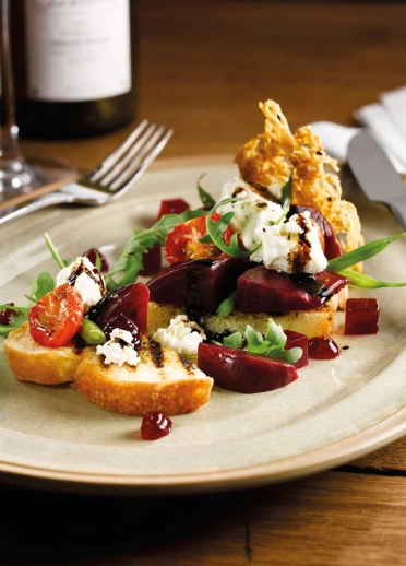 A dish of tomatoes, lettuce, beetroot cheese and crostini.
