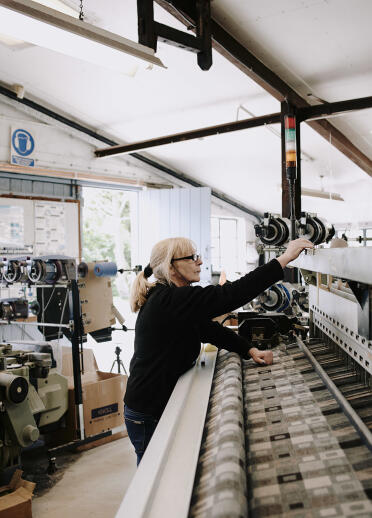 Woman operating woollen mill machinery