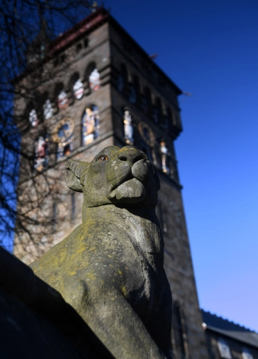 Cardiff Castle clock tower with a stone animal in front.