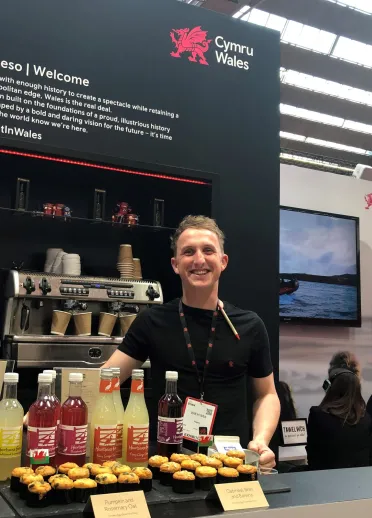 Staff member exhibiting Welsh food and drink on the Wales stand.