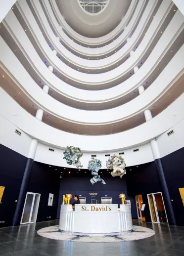 White reception desk with St David's gold lettering cherubs hanging from ceiling and 7 white floor balconies.
