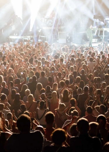 A crowd of people watching a concert in an indoor venue