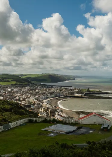 view of Aberystwyth coat with white clouds blue sky and mountains in teh background