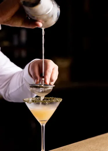 drink being poured into a cocktail glass