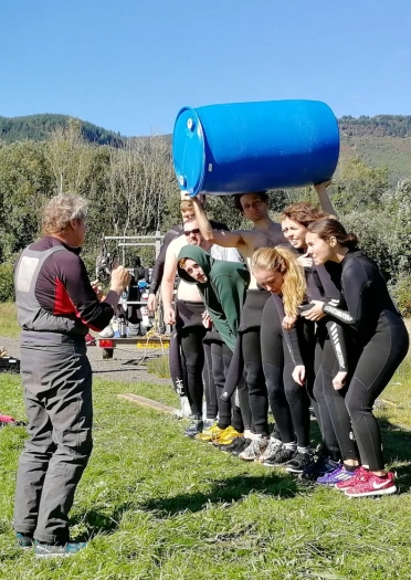 A group team building on an assault course including planks and barrels.