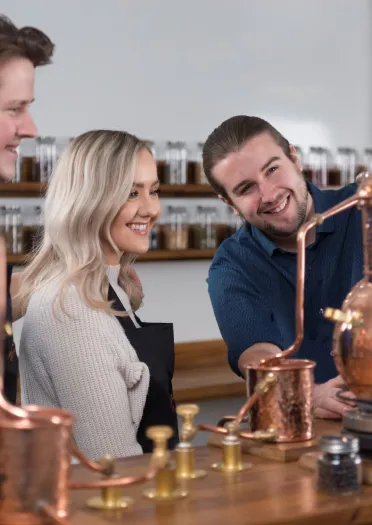 A man showing a couple around a distillery.