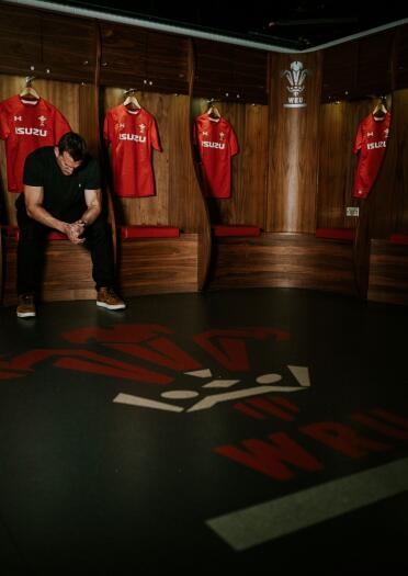 Sam Warburton sitting in the players dressing room surrounded by rugby shirts.