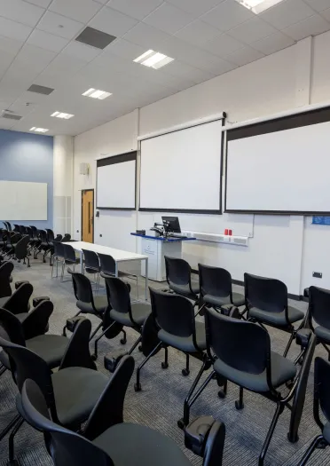 Chairs in a breakout meeting room facing projector screens.
