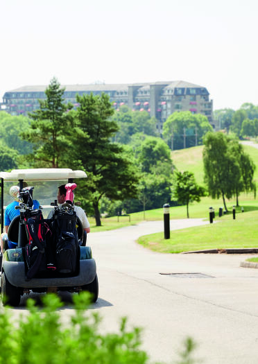People in a golf buggy on the course travelling to the resort hotel.