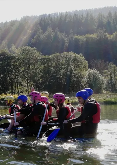 Adult group on raft in a river wearing safety equipment.