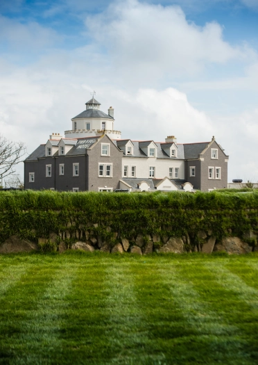 Exterior of hotel viewed from beyond the lawn and hedges.