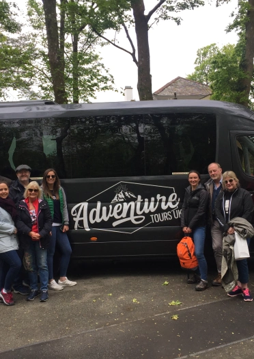 Group of people standing outside mini bus.