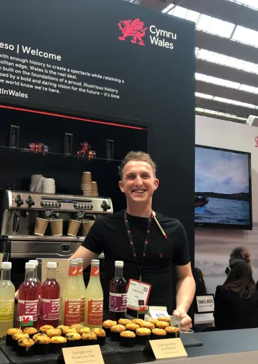 Staff member exhibiting Welsh food and drink on the Wales stand.