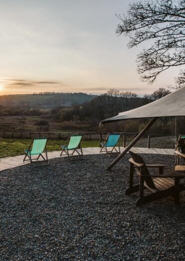 Tipi and chairs with hills and sunset in distance.
