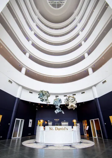 White reception desk with St David's gold lettering cherubs hanging from ceiling and 7 white floor balconies.