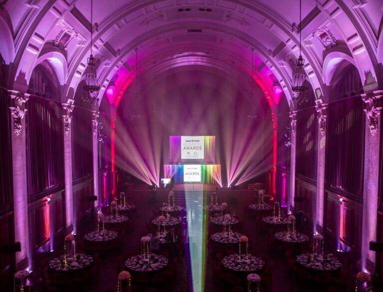 A university hall lit up and laid out for a gala dinners for an awards evening.