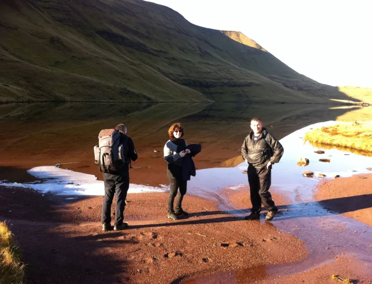 A group of people standing near a mountain.
