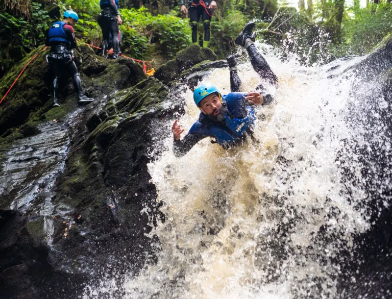 A man canyoning down rapids wearing safety gear.
