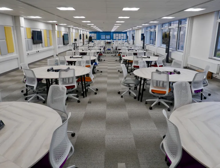 A long meeting room with round tables at a university.