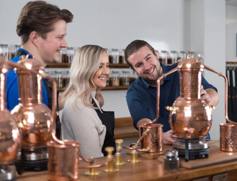 A man showing a couple around a distillery.