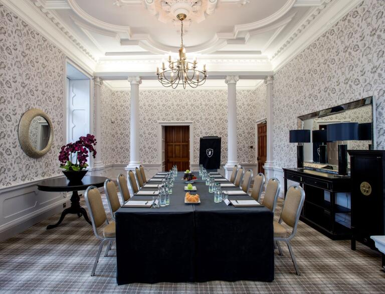 A conference room with tartan carpet and a chandelier hanging from ceiling.