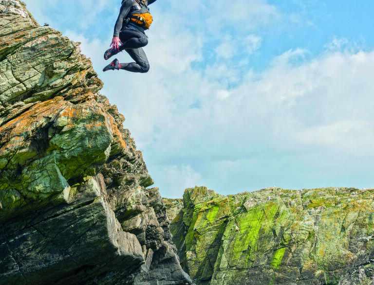 Man jumping from a rock into the sea while coasteering.