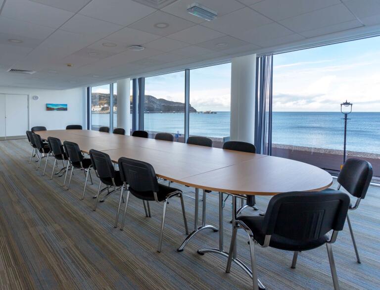 Boardroom with floor to ceiling windows looking out to sea.