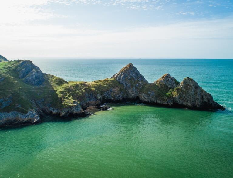 Three cliffs with water and blue sky.