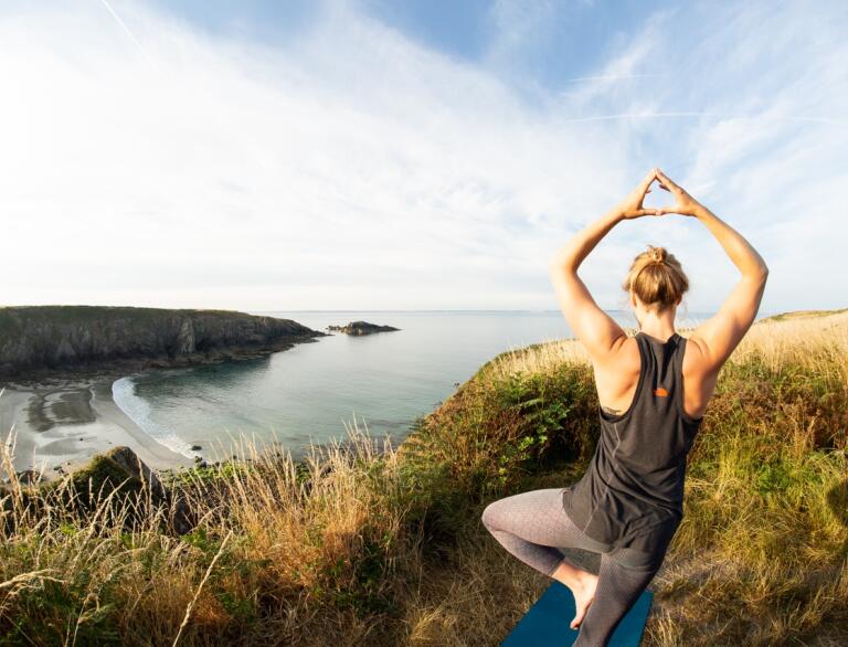 Person doing yoga overlooking beach.