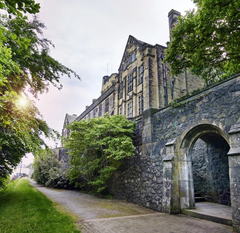 An external view of a university alongside a path lined with greenery.