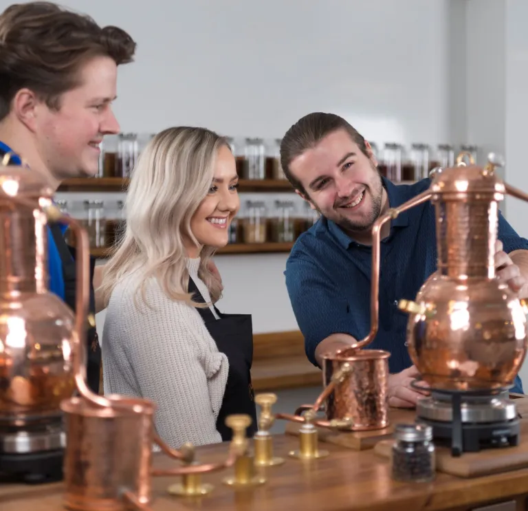 A man showing a couple around a distillery.